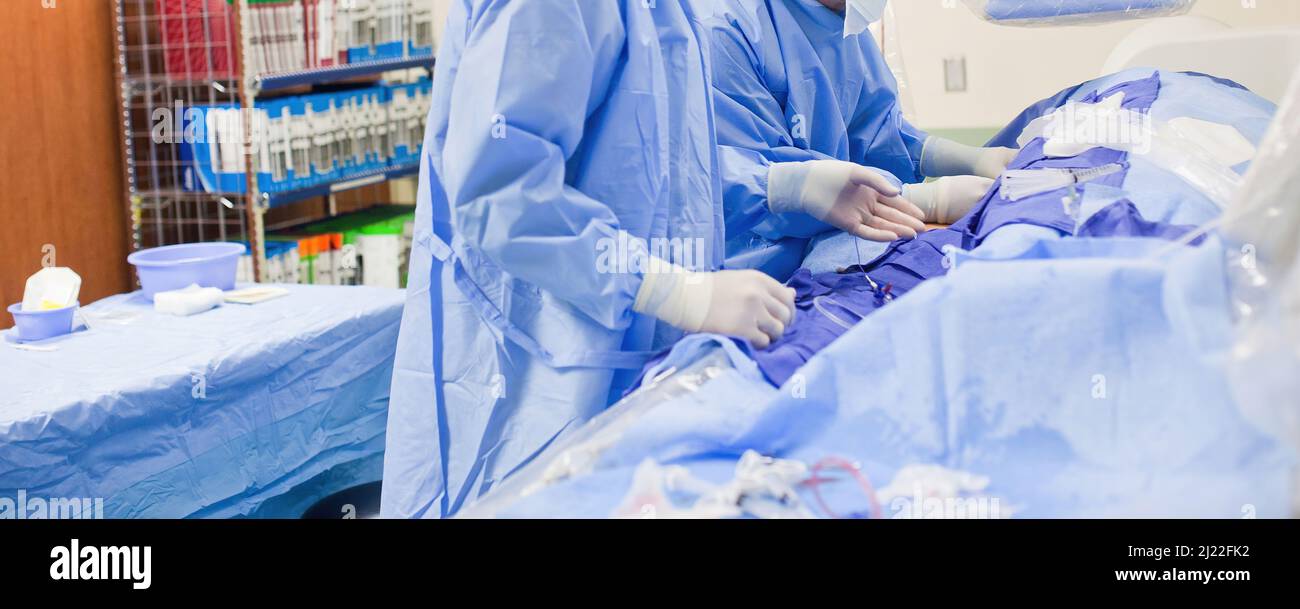 Deux médecins chirurgiens non-descript effectuant une chirurgie dans une salle chirurgicale portant des exfoliants bleus et des gants en latex blanc Banque D'Images