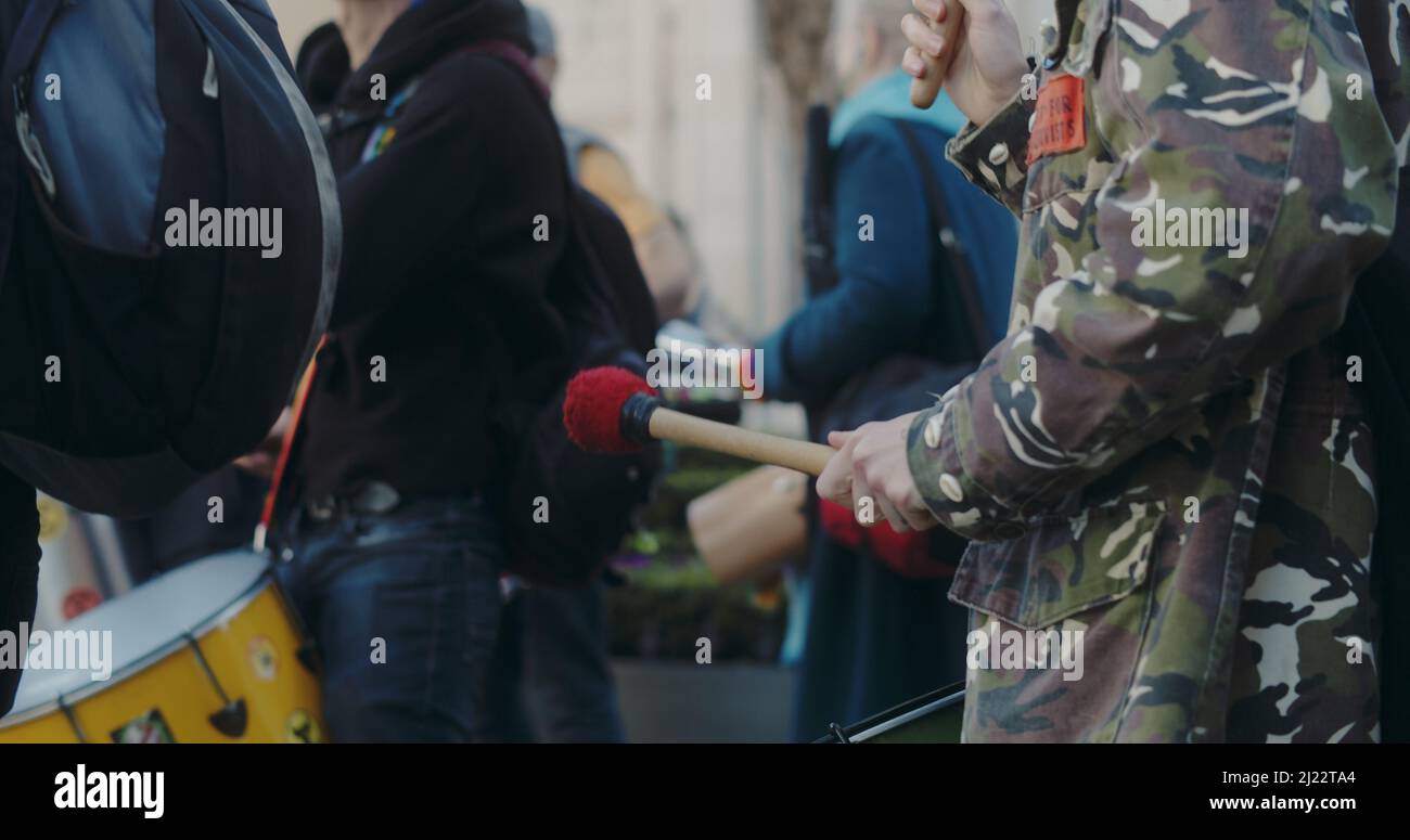 Londres, Royaume-Uni - 03 19 2022: Une femme extinction rébellion climat manifestant jouer à la percussion battant sur un tambour, à Portland place. Banque D'Images