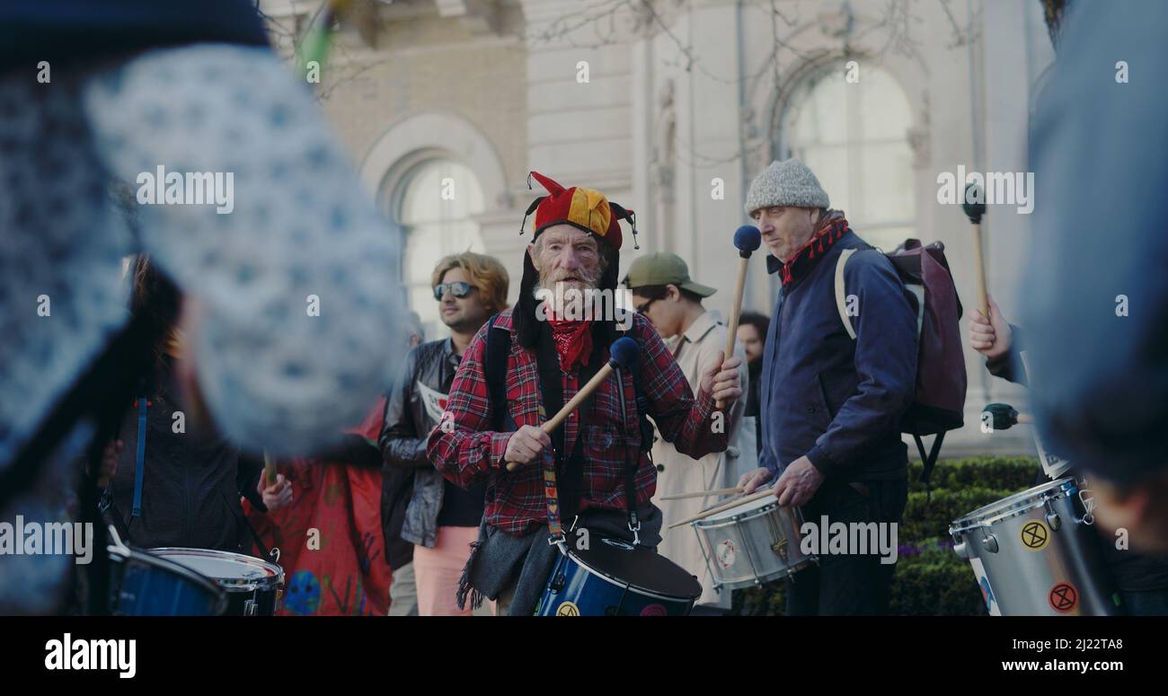 Londres, Royaume-Uni - 03 19 2022: Old man extinction rébellion climat manifestant jouer à la percussion battant sur un tambour, à Portland place. Banque D'Images