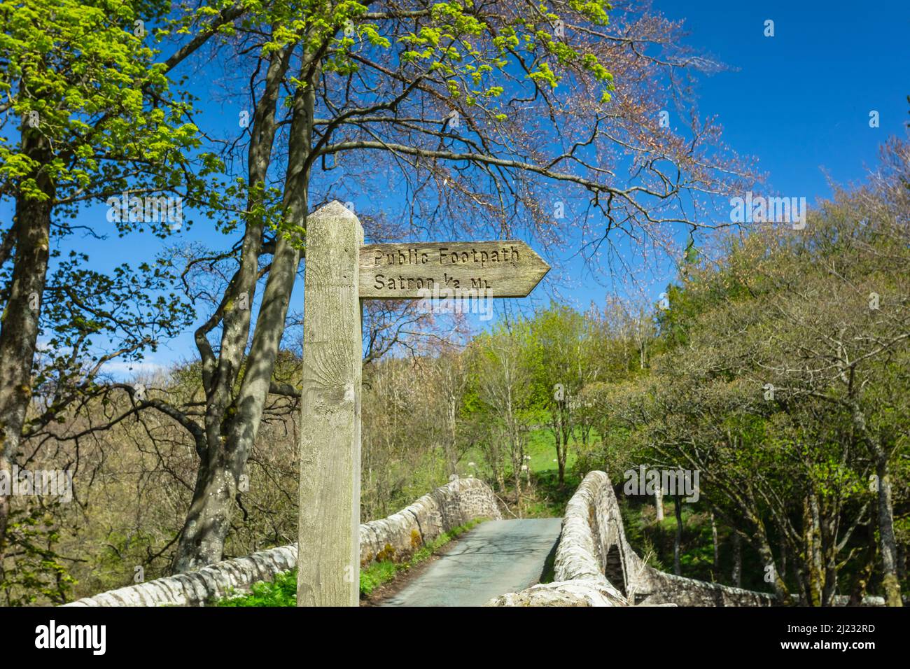 Sentier public signe de Satron, un hameau rural de Swaledale, avec 16th siècle Ivelet Bridge en arrière-plan. Printemps dans le Yorkshire Dales wi Banque D'Images