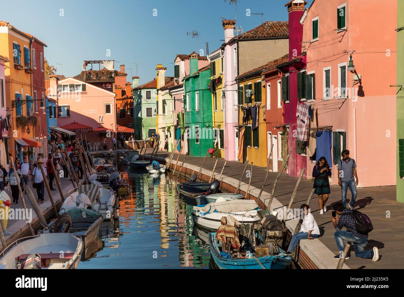 Italie, Venise, maisons colorées sur l'île vénitienne de Burano reflétant un canal Banque D'Images