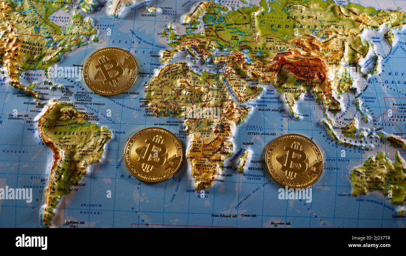 Pièces de bitcoin en métal d'or sur une carte du monde de secours de 3D. Banque D'Images