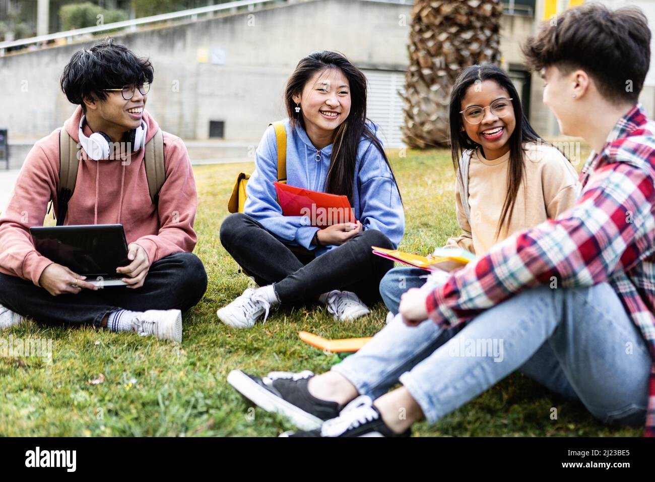 Jeunes étudiants assis à l'herbe à l'université de campus Banque D'Images