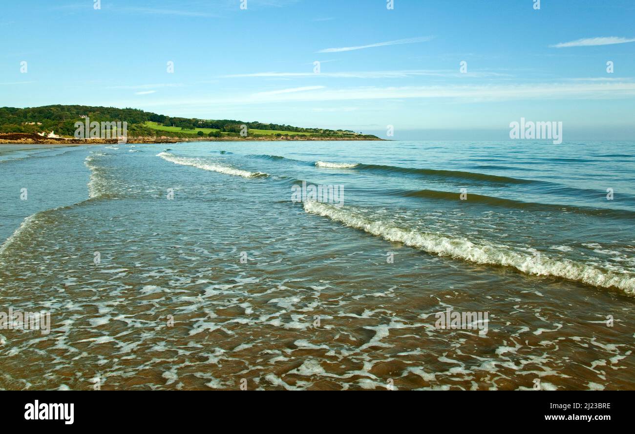 Vagues douces se déroulant sur la plage de Traayeth ora dans la baie de Dulas, vue depuis le sentier côtier de l'île d'Anglesey, au nord du pays de Galles, au Royaume-Uni, Banque D'Images