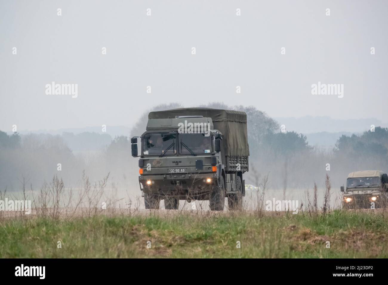Un petit convoi de véhicules utilitaires intermédiaires Land Rover Defender Wolf de l'armée britannique et un CAMION logistique 4x4 SV D'HOMME lors d'un exercice militaire Banque D'Images