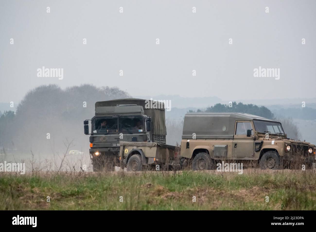 Un petit convoi de véhicules utilitaires intermédiaires Land Rover Defender Wolf de l'armée britannique et un CAMION logistique 4x4 SV D'HOMME lors d'un exercice militaire Banque D'Images
