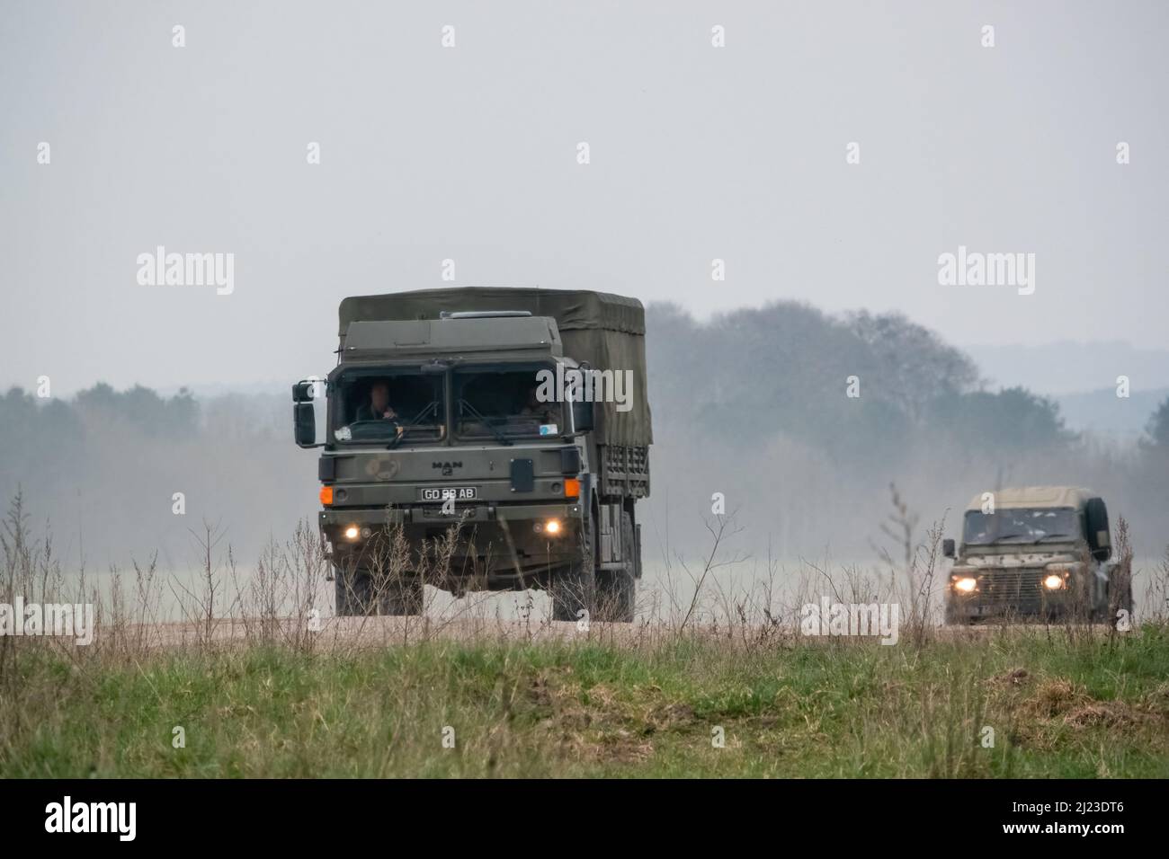 Un petit convoi de véhicules utilitaires intermédiaires Land Rover Defender Wolf de l'armée britannique et un CAMION logistique 4x4 SV D'HOMME lors d'un exercice militaire Banque D'Images
