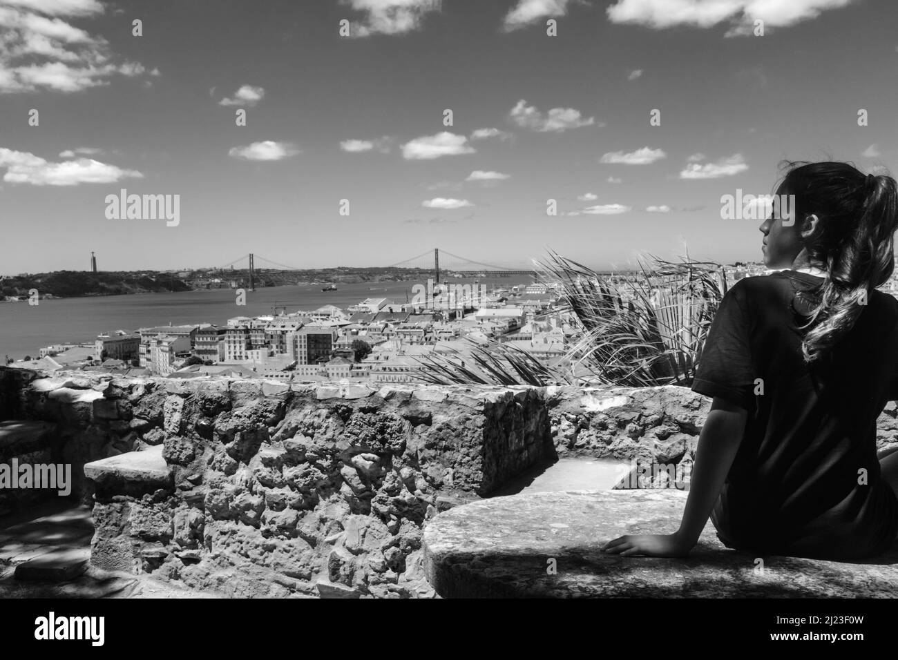 Elle est assise sur un banc avec vue sur la ville historique de Lisbonne. Rivière Tage en arrière-plan Banque D'Images