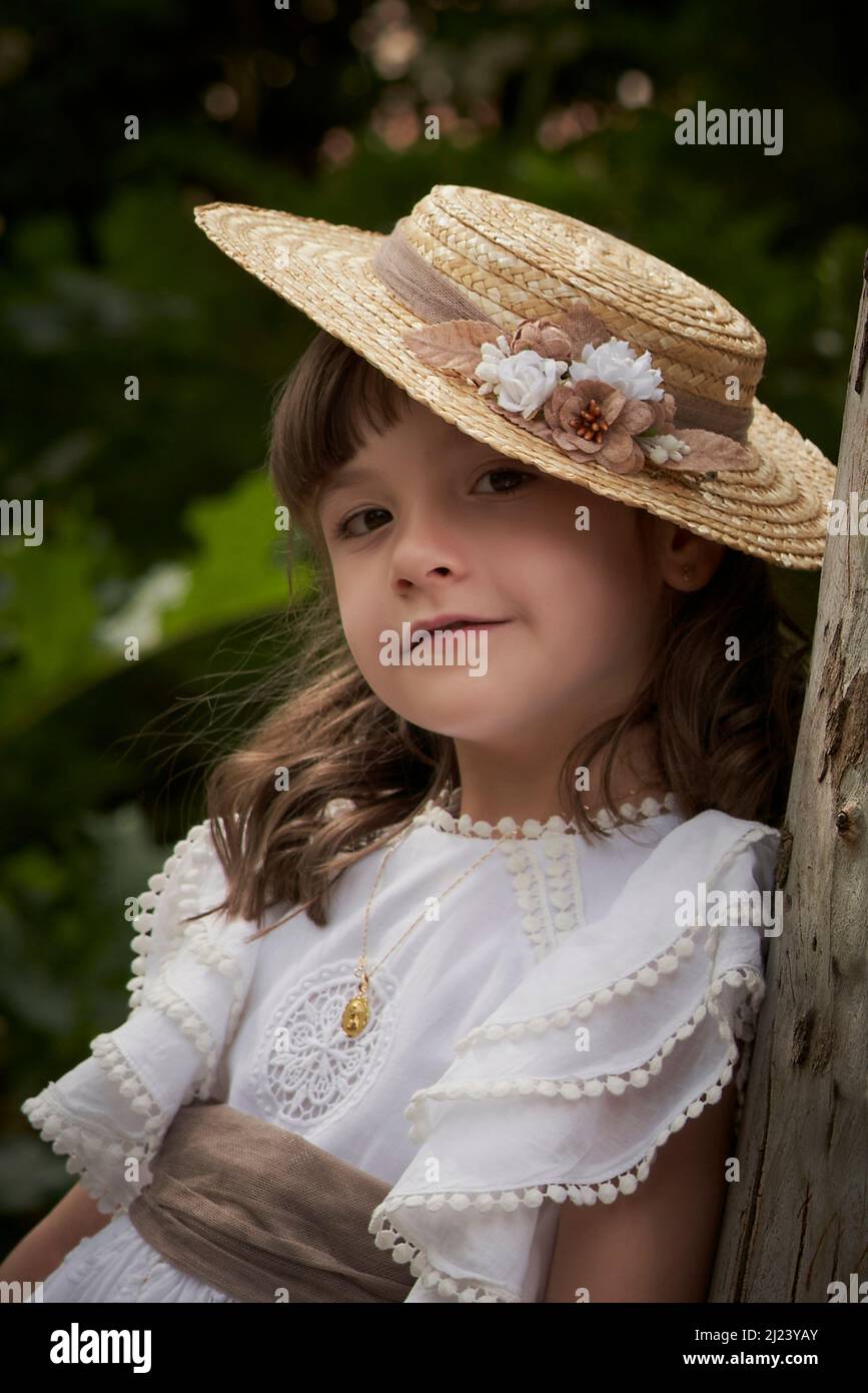 Communion fille posant à côté d'un grand arbre dans un parc Banque D'Images