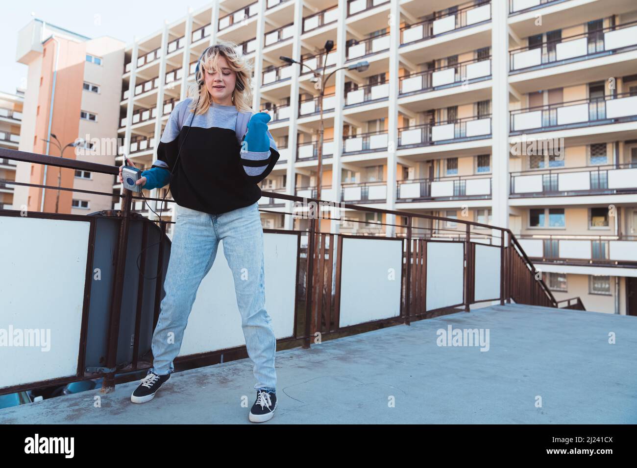 90s vibes. Photo plein air d'une jeune fille d'hipster dansant tout en portant son casque et en tenant un lecteur de cassettes à l'ancienne. Photo de haute qualité Banque D'Images