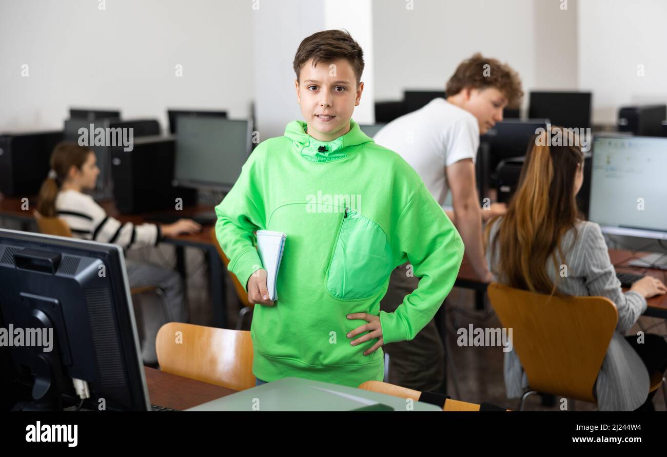 Préteen élève avec des livres de travail dans les mains debout dans la classe d'ordinateur Banque D'Images