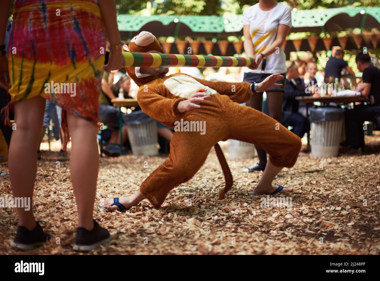 Monkeying autour. Un gars vêtu d'un costume de singe qui fait la danse limbo lors d'un festival de musique. Banque D'Images