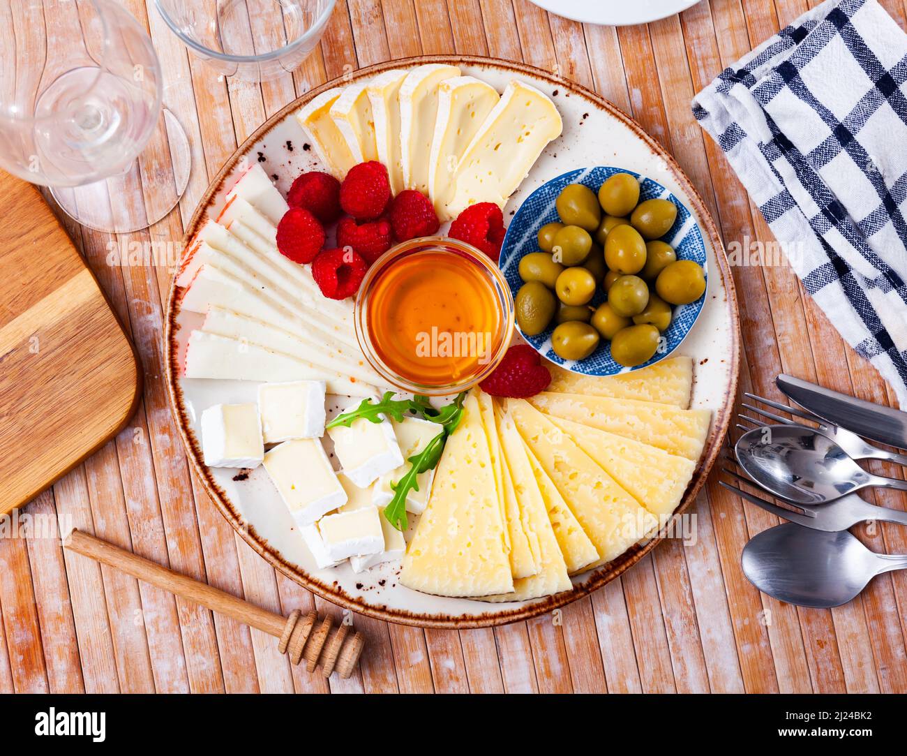 Assiette avec différents types de fromage, framboises et olives Banque D'Images