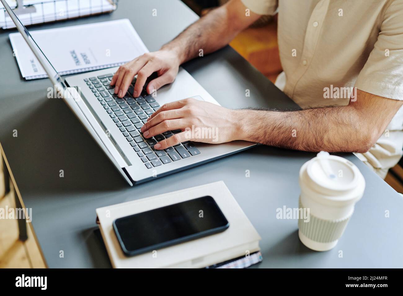 Les mains d'un jeune homme d'affaires tapant sur un clavier d'ordinateur portable sur son lieu de travail tout en analysant des données financières en ligne Banque D'Images