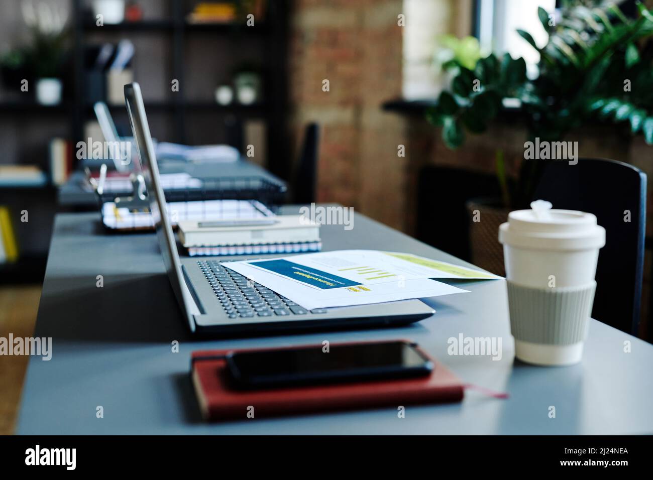 Tasse de café, ordinateur portable, smartphone, ordinateur portable avec documents financiers sur clavier sur le lieu de travail de l'économiste contemporain Banque D'Images