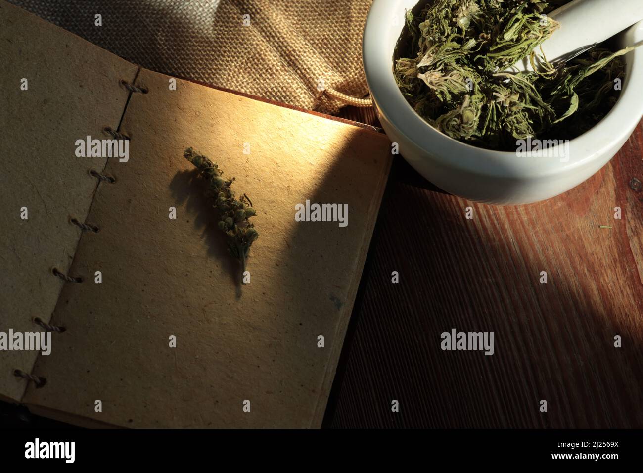 Vue de dessus d'un bol de tisane verte séchée et d'un carnet vintage vierge sur la table en bois Banque D'Images