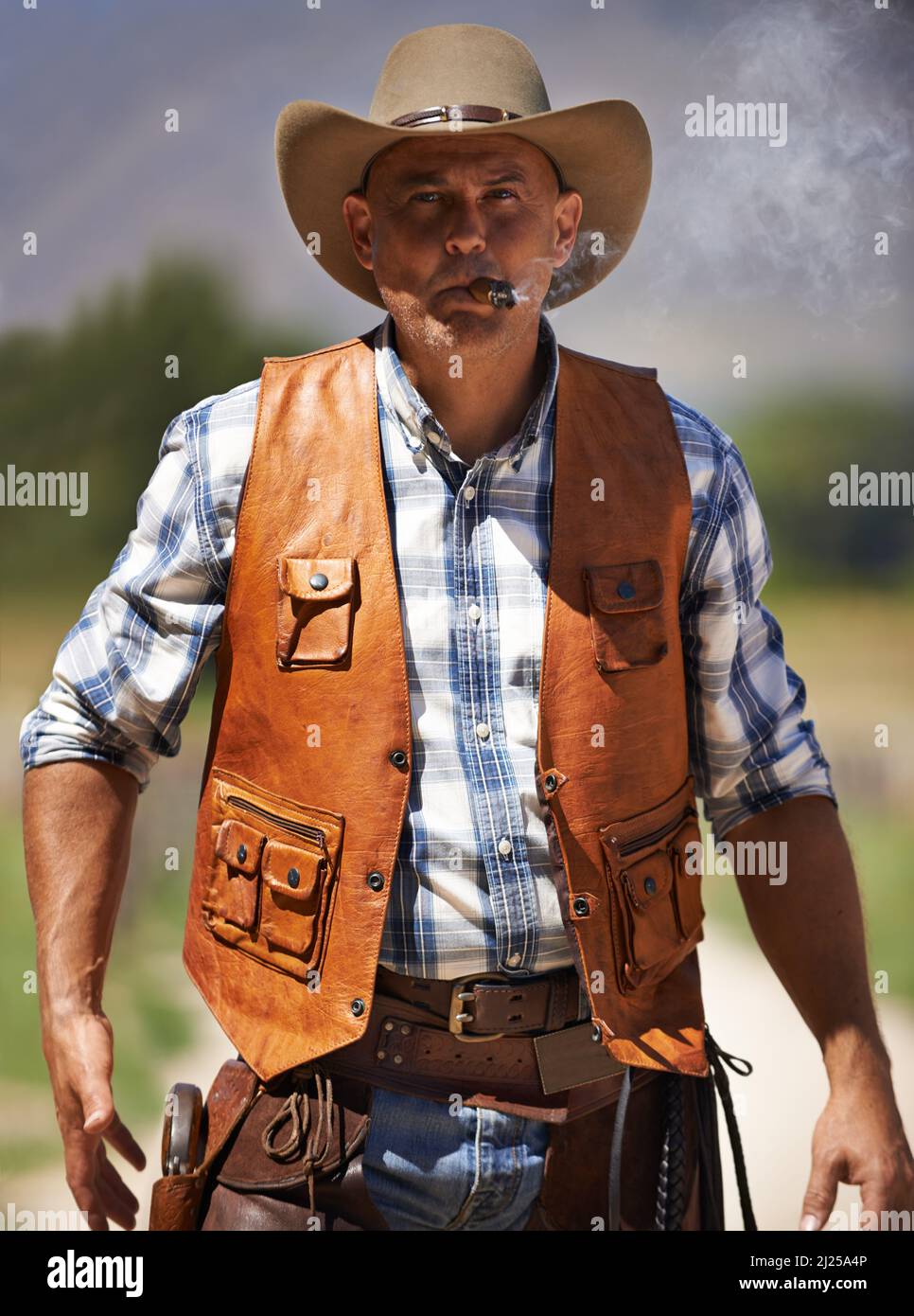 HES le wrangler des bêtes. Un cowboy mature à l'extérieur avec son fusil tiré. Banque D'Images