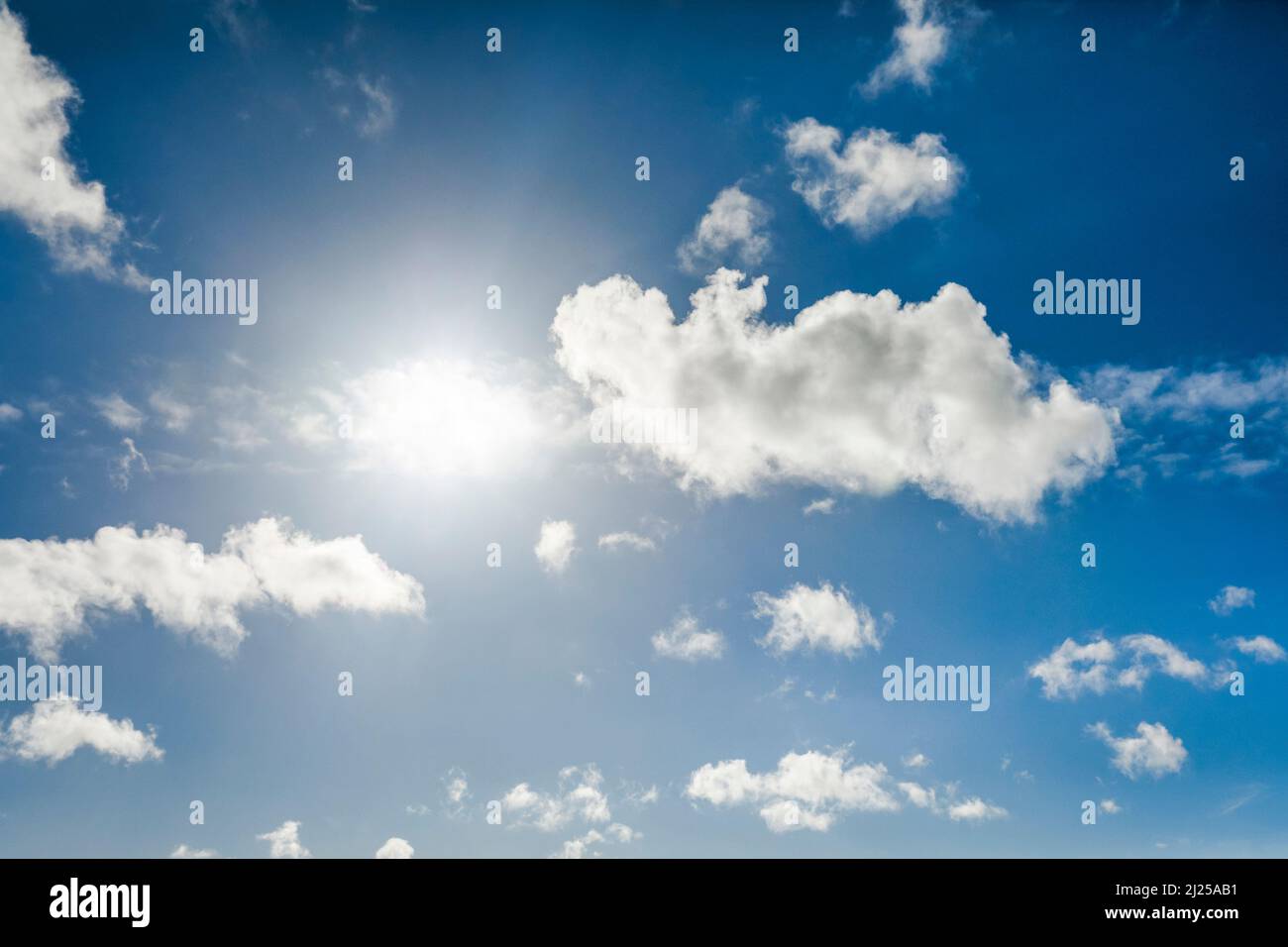 Le soleil rétro-éclaire les nuages cumulus dans le ciel bleu Banque D'Images