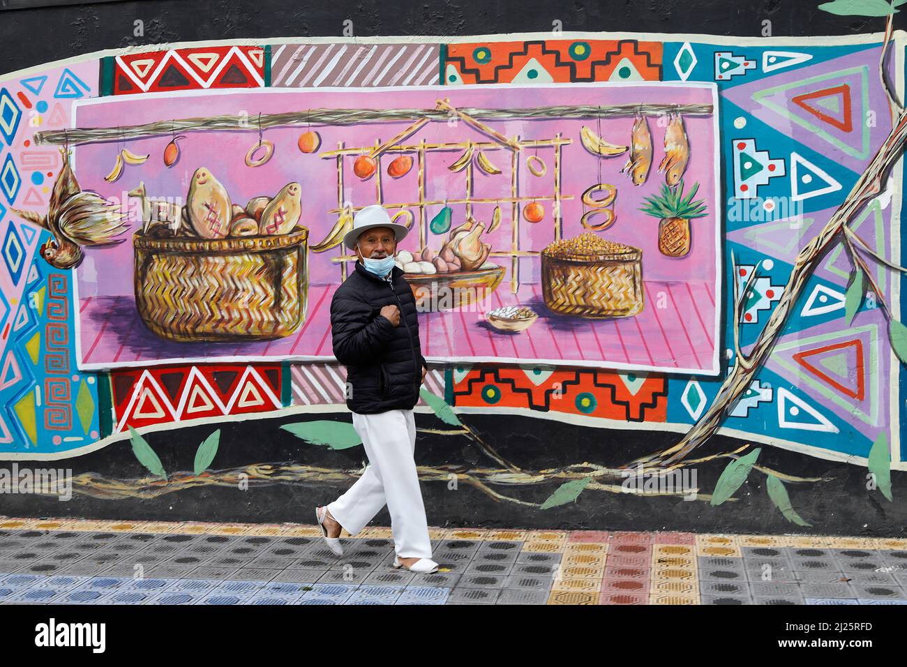 Homme marchant devant des peintures murales à Otavalo, Equateur Banque D'Images