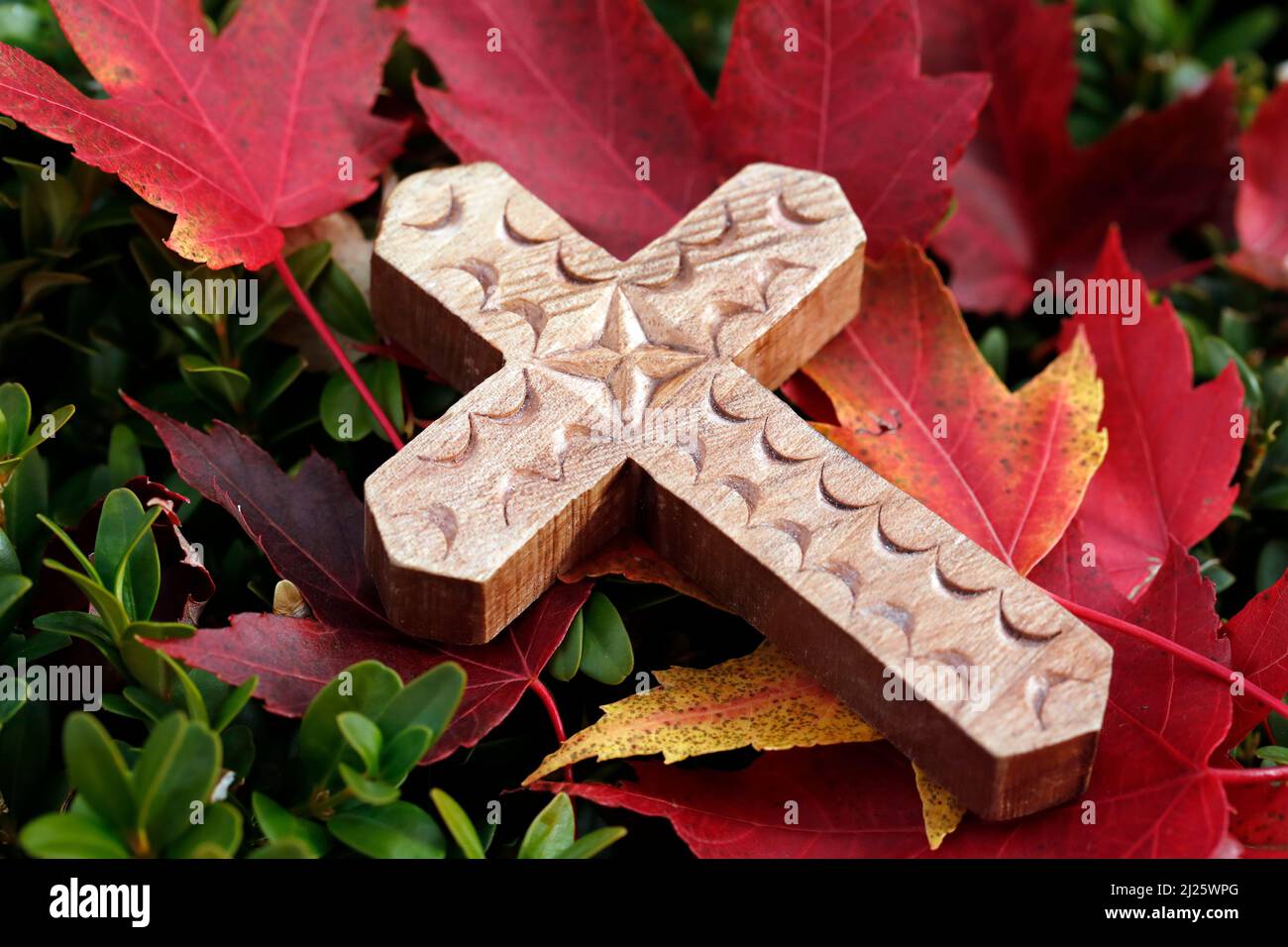 Croix en bois chrétien avec congé rouge d'automne. Banque D'Images