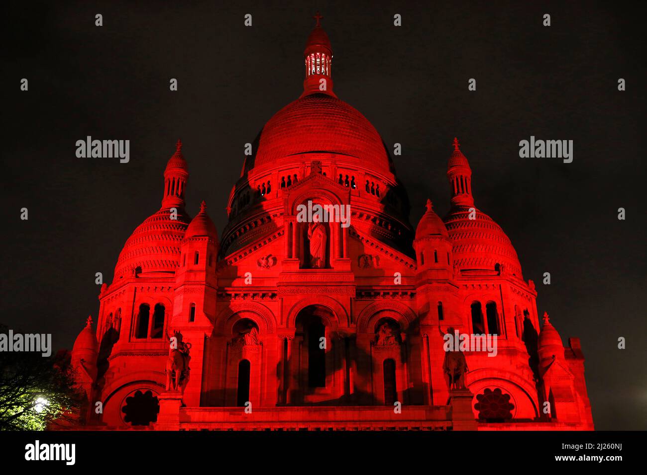 La basilique du Sacré-cœur illuminée en rouge par la charité d'aide a l'Eglise en Detresse, Paris, France Banque D'Images