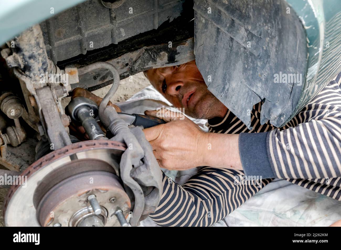 Homme changeant un pneu et fixant une roue après une panne dans un village près de Soroca, Moldavie Banque D'Images