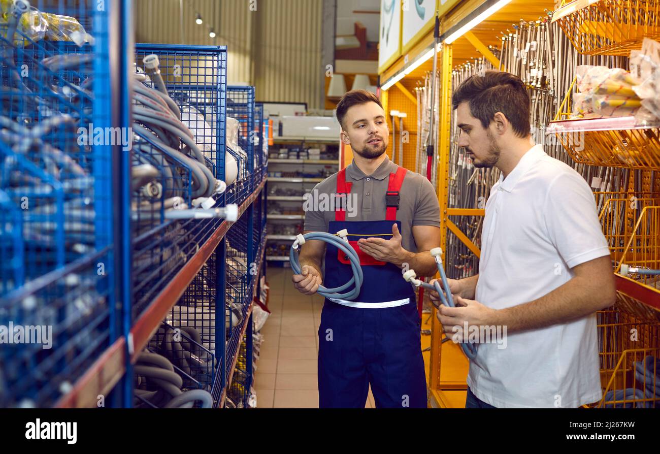 Le vendeur dans le magasin de matériaux de construction conseille l'acheteur sur les tuyaux pour les machines à laver ou les lave-vaisselle. Banque D'Images