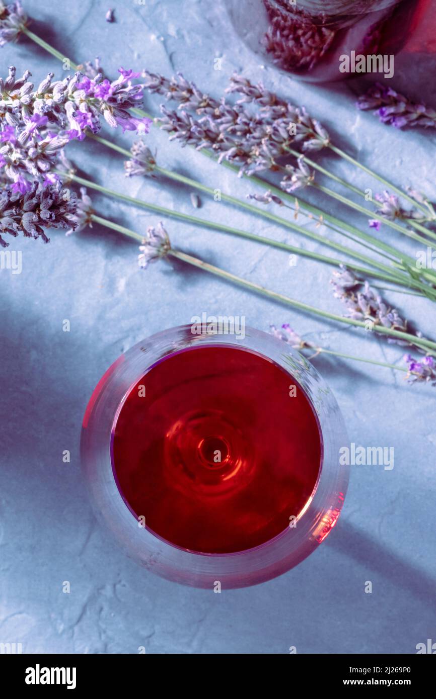 Gros plan de vin de rose avec fleurs de lavande, tiré d'en haut sur une table avec ombres Banque D'Images