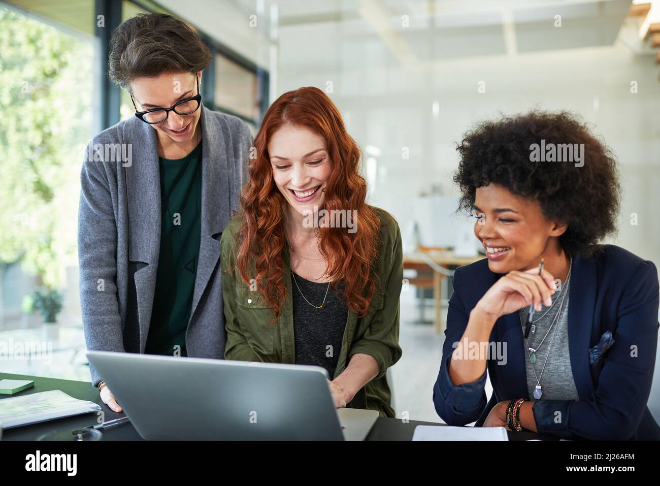 Fixer de nouveaux sommets avec leurs compétences. Photo rognée de trois jeunes créatifs travaillant ensemble sur un ordinateur portable dans un bureau moderne. Banque D'Images