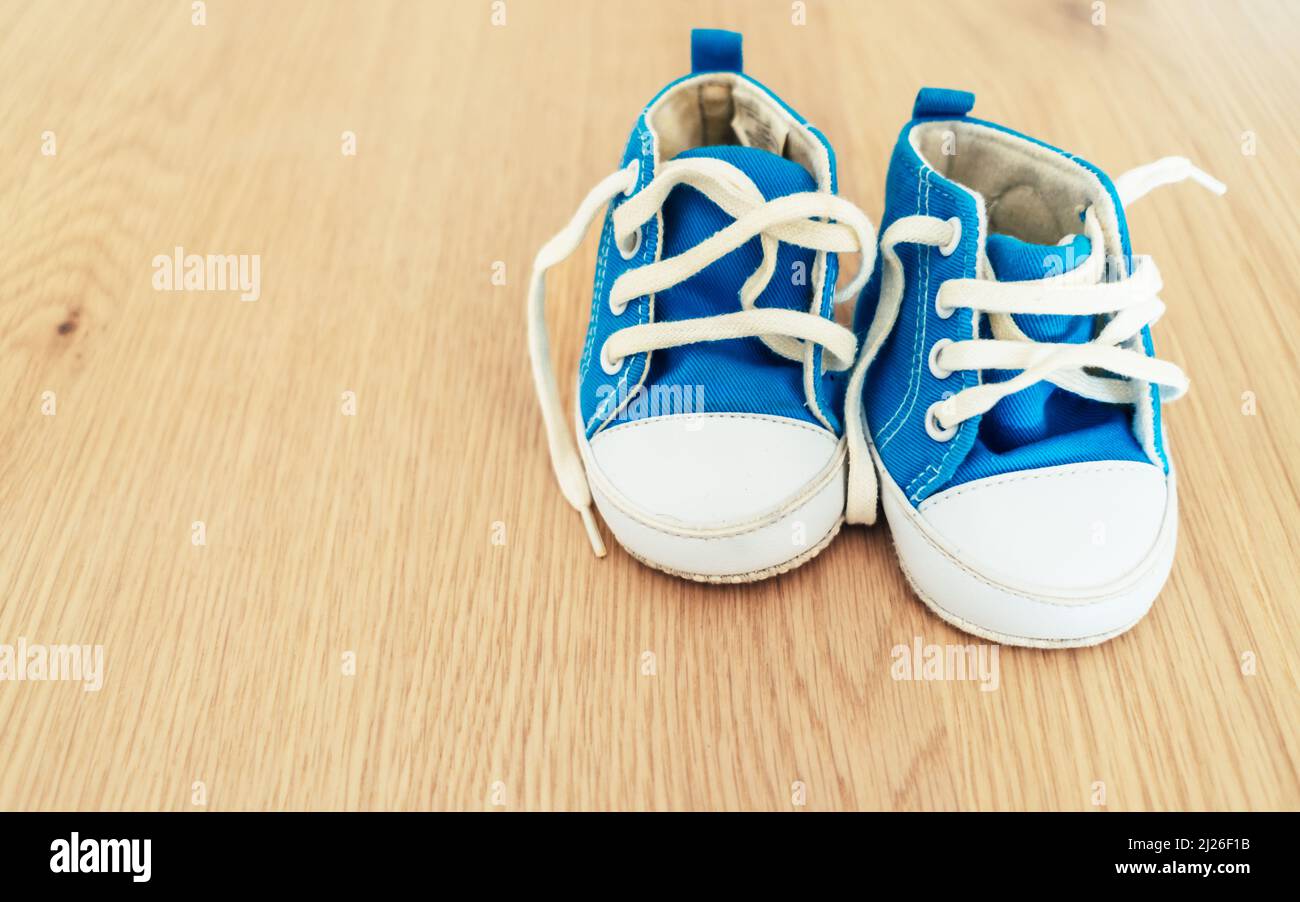 Paire de sneakers bleues et blanches pour bébé sur fond en bois. Banque D'Images