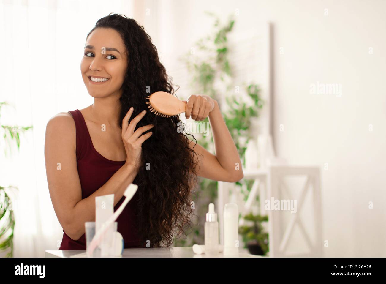 Bonne dame faisant les routines de beauté du matin, brossant les cheveux  longs avec une brosse en bois devant le miroir à la maison Photo Stock -  Alamy