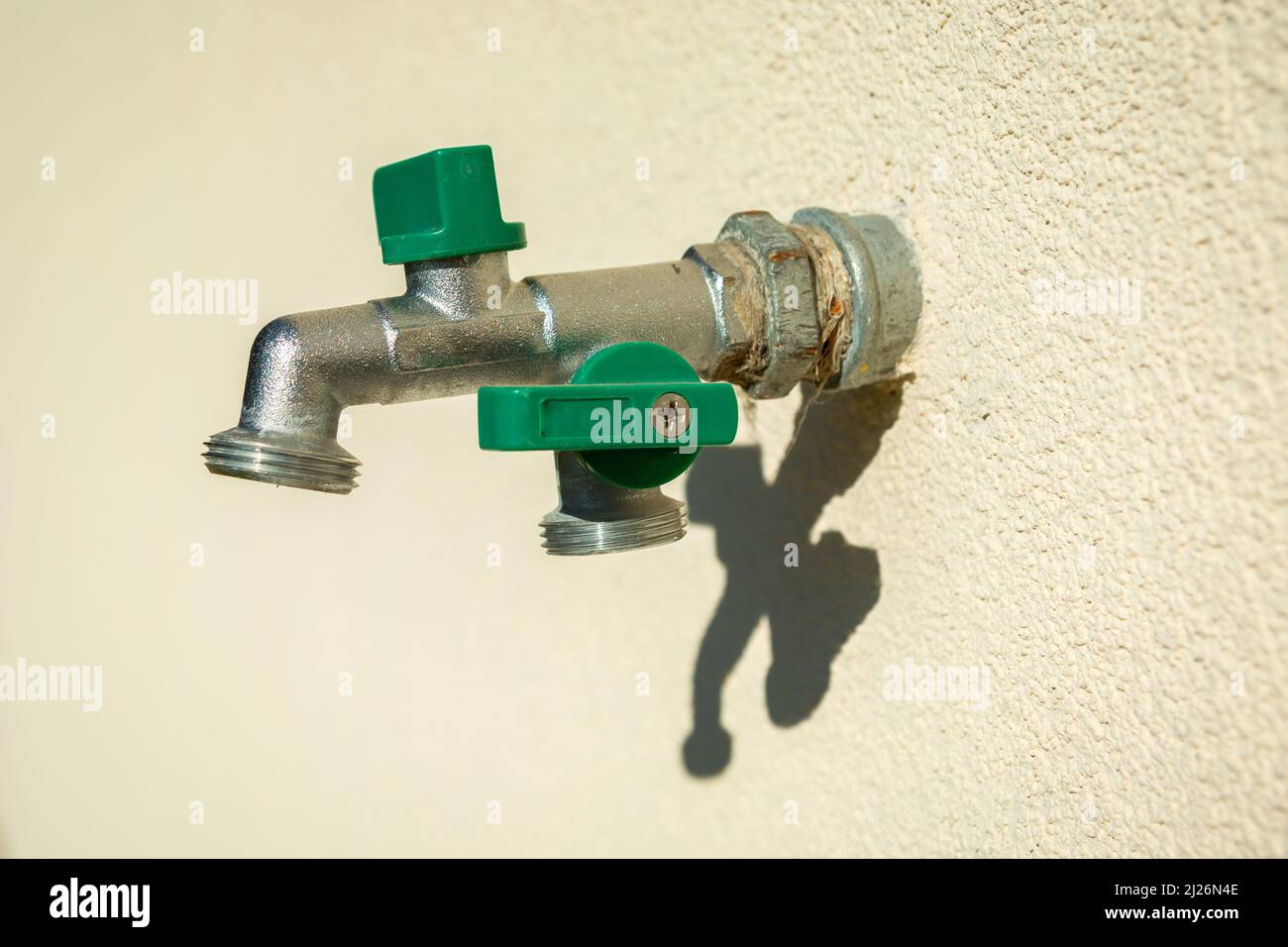 Un double robinet de jardin en laiton monté dans le mur lumineux Banque D'Images