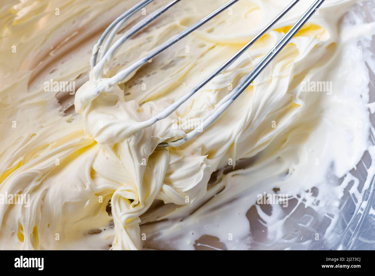 Double crème fouettée dans un bol avec un fouet à la main Banque D'Images