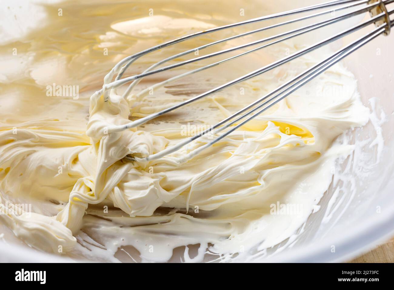 Double crème fouettée dans un bol avec un fouet à la main Banque D'Images