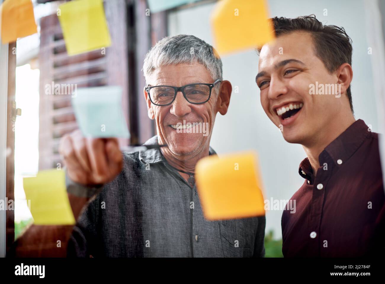 Ce plan gagnant allait réussir. Photo de deux hommes d'affaires de brainstorming avec des notes sur un mur de verre dans un bureau. Banque D'Images