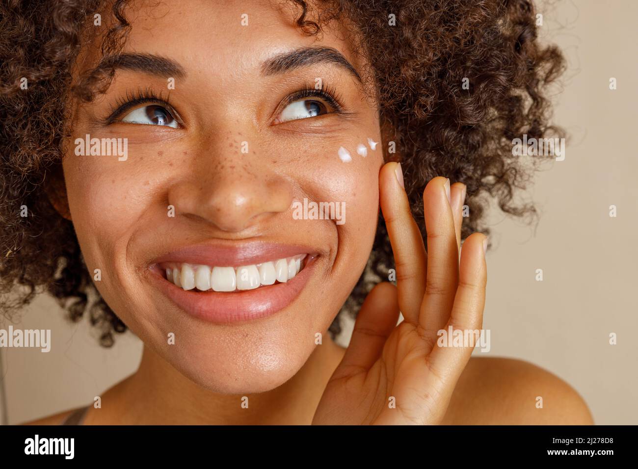 Jeune femme avec de la crème sur le visage en studio Banque D'Images