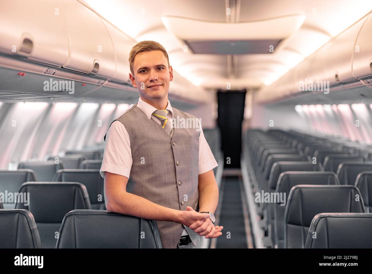 Un agent de bord masculin se tenant dans le salon de passagers de l'avion Banque D'Images