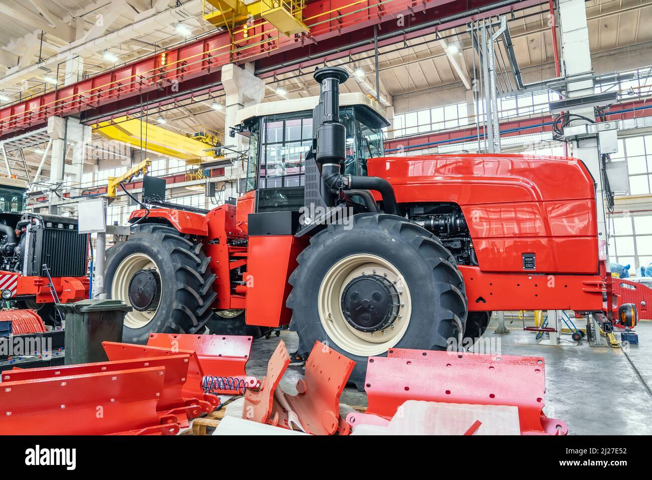 Gros tracteur ou moissonneuse rouge en cours d'assemblage en usine sur la chaîne de production pour la fabrication de machines agricoles. Banque D'Images