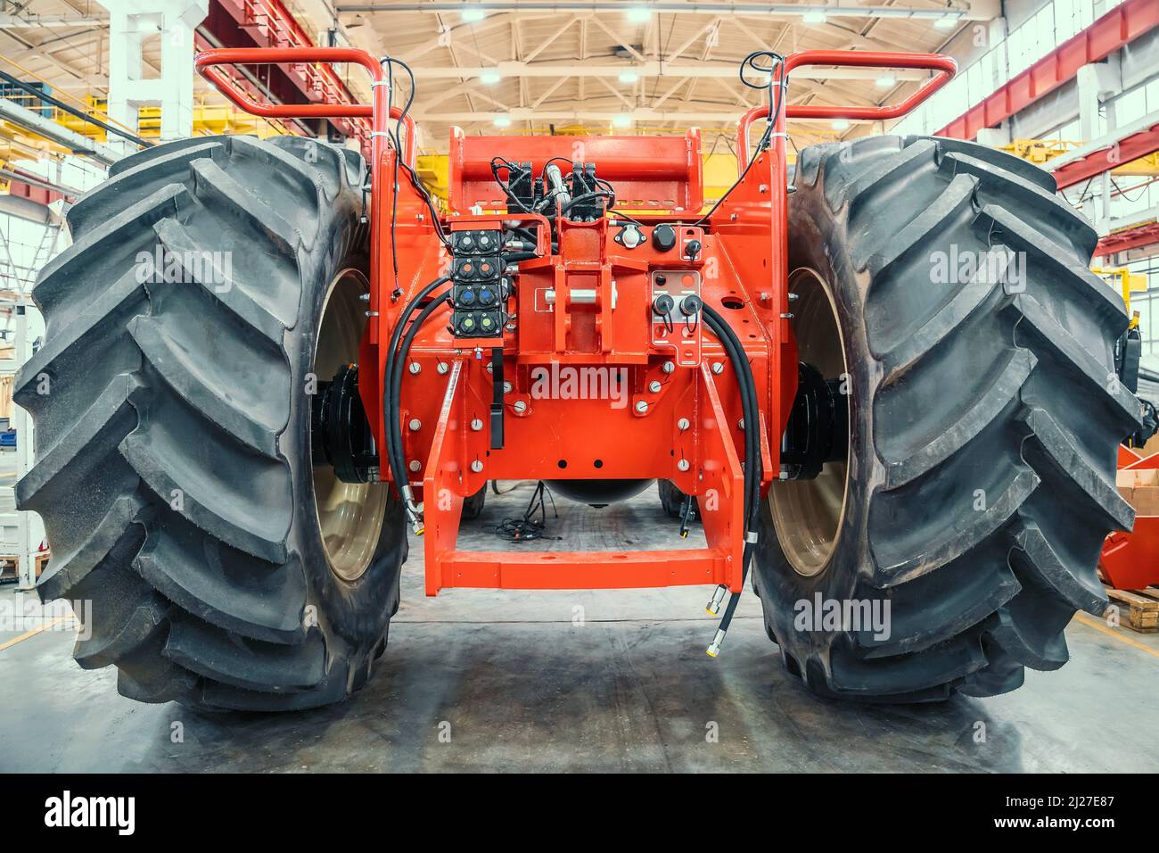 Gros tracteur ou moissonneuse rouge en cours d'assemblage en usine sur la chaîne de production pour la fabrication de machines agricoles. Banque D'Images