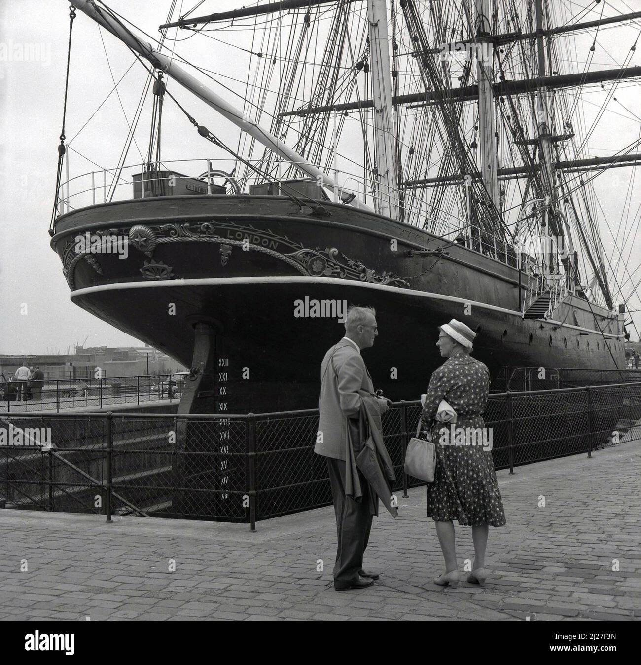 1950s, historique, un gentleman et une dame debout à l'arrière ou à la poupe du voilier, le Cutty Sark, Greenwich, Londres, Angleterre, ROYAUME-UNI. Construit en Écosse en 1869 pour transporter le thé de retour de Chine, le bateau à trois mâts était célèbre pour ses passages record. Banque D'Images