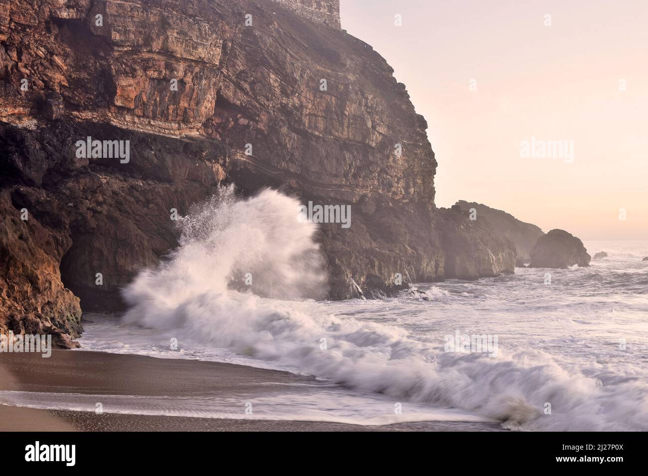 Praia do Norte (plage nord) les vagues se brisent sur la falaise à Nazaré Portugal. Banque D'Images