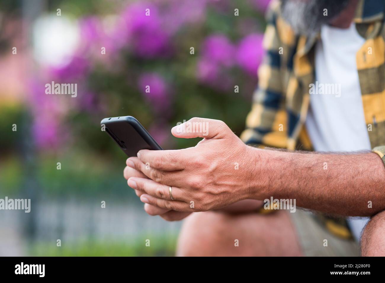 Gros plan sur les mains d'homme mûr tapant et écrivant sur un téléphone mobile. Les hommes font passer les mains des gens à l'aide de l'application sur un smartphone en extérieur Concept de rencontres en ligne et wir Banque D'Images