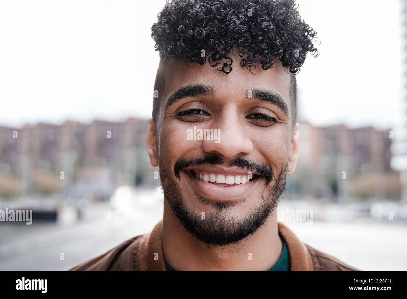 Jeune latino souriant sur l'appareil photo extérieur - Focus sur le visage Banque D'Images