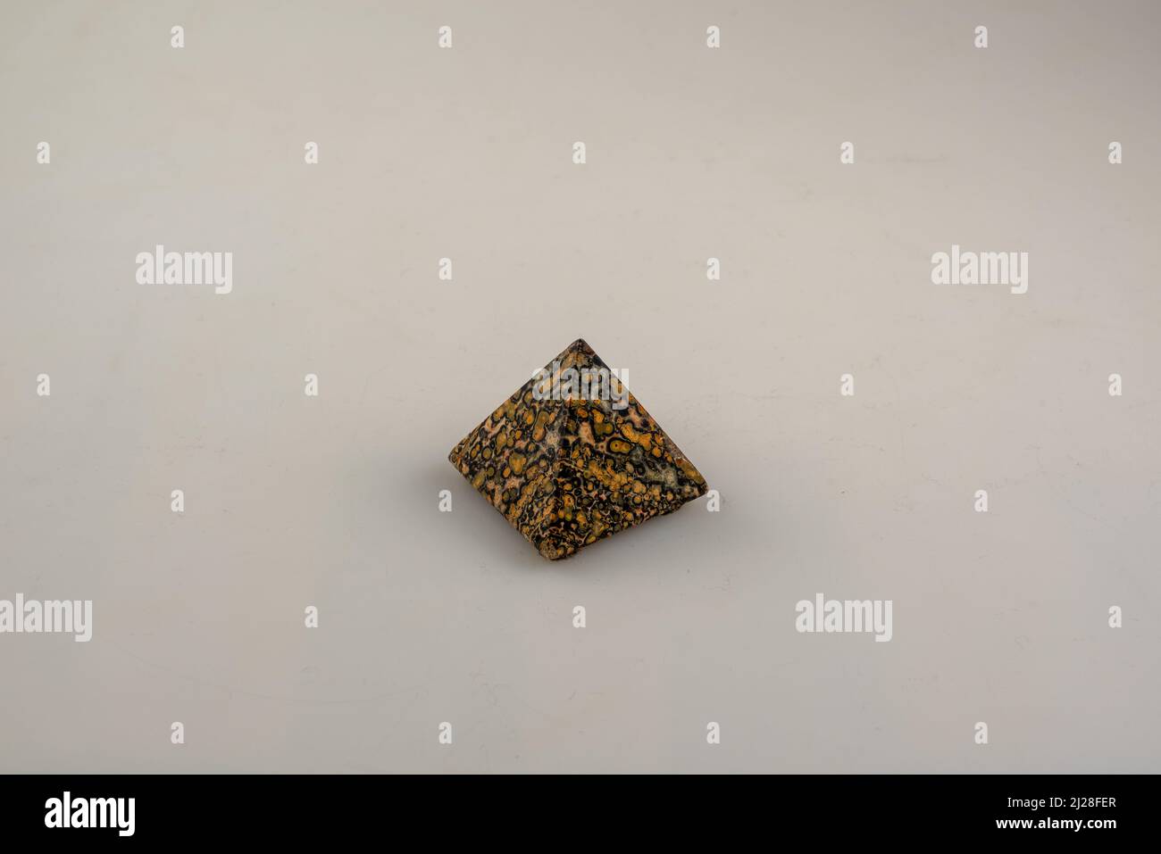 une petite pyramide avec un voile orange et noir sur un fond clair Banque D'Images