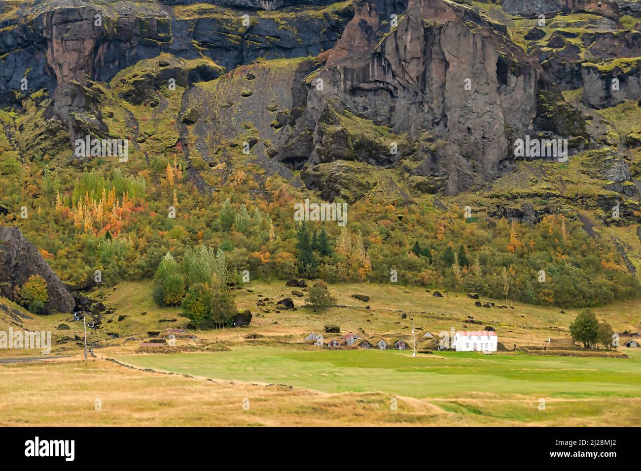 Maison de ferme et maisons en gazon près d'une montagne de lave avec des couleurs d'automne dans le sud de l'Islande. Banque D'Images