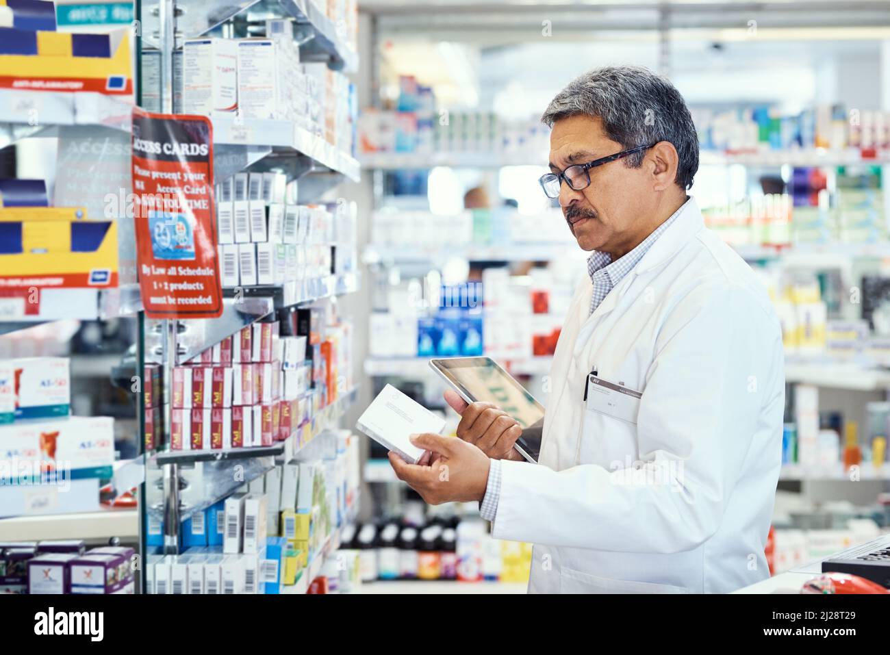 Gestion des questions médicales dans sa pharmacie. Prise de vue d'un pharmacien mature utilisant une tablette numérique tout en travaillant dans un chimiste. Banque D'Images