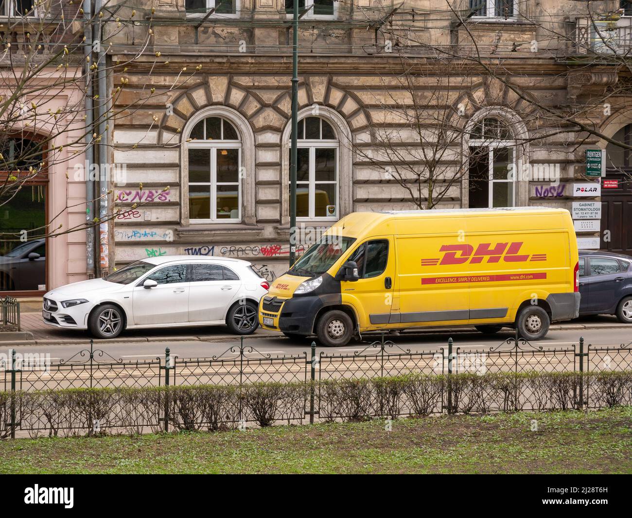 Service de livraison de colis DHL camion, camionnette, véhicule stationné dans la rue à proximité d'un bâtiment, compagnie de messagerie logistique allemande DHL, zone urbaine, Cracovie, Polan Banque D'Images