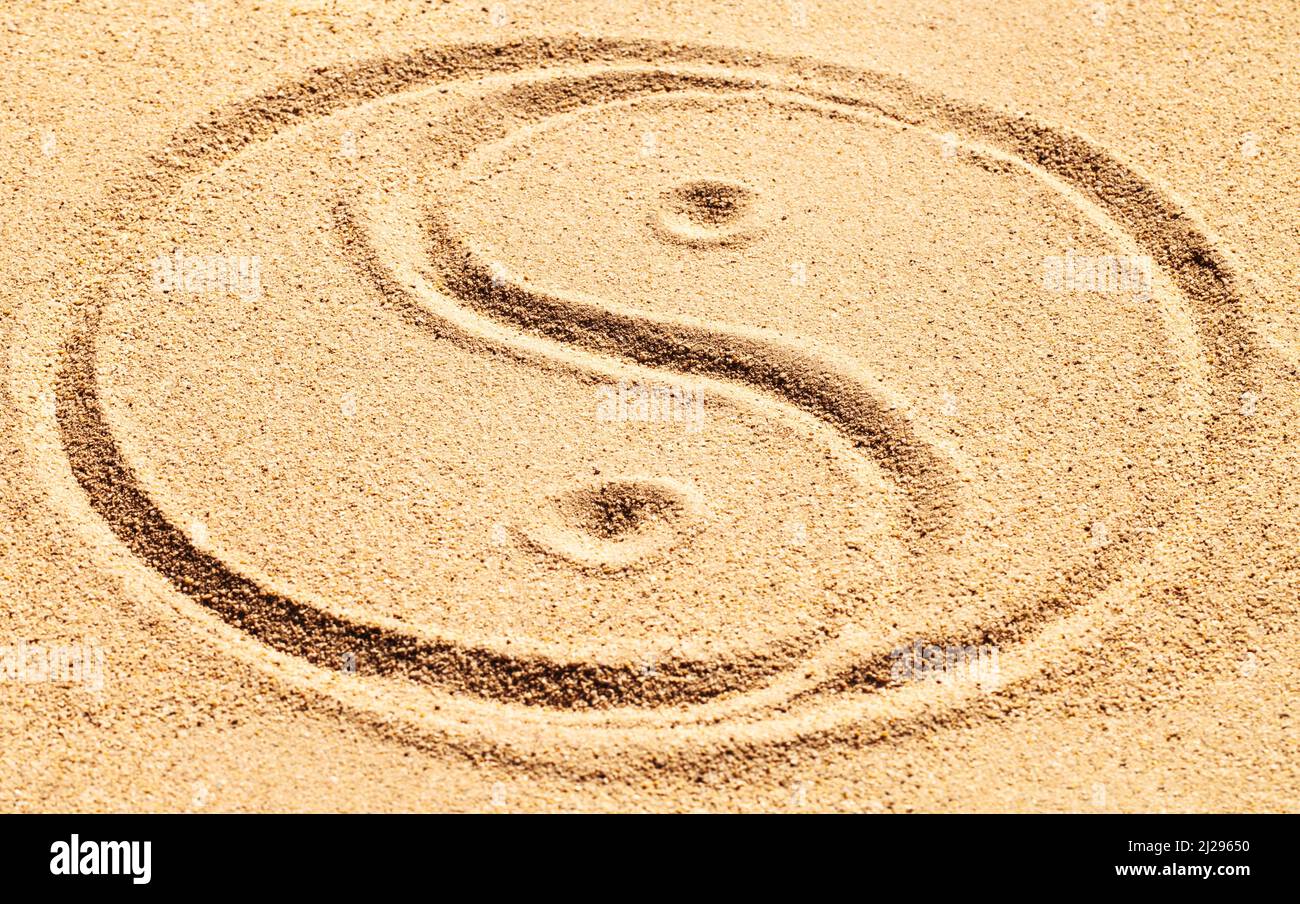 L'équilibre est réalisable. Photo d'un symbole yin et yang dessiné dans le sable. Banque D'Images