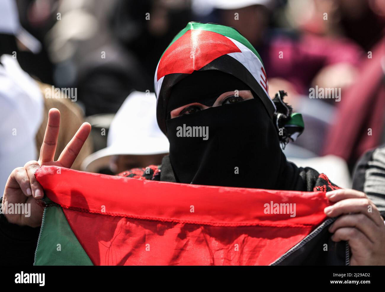 Gaza, Palestine. 30th mars 2022. Une femme portant un foulard aux couleurs du drapeau palestinien fait un V lors d'un rassemblement pour commémorer l'anniversaire de la Journée des terres de 46th au port de Gaza. La Journée des terres marque un incident qui a eu lieu en 1976 lorsque les troupes israéliennes ont abattu six personnes lors de manifestations contre les confiscations de terres. Crédit : SOPA Images Limited/Alamy Live News Banque D'Images