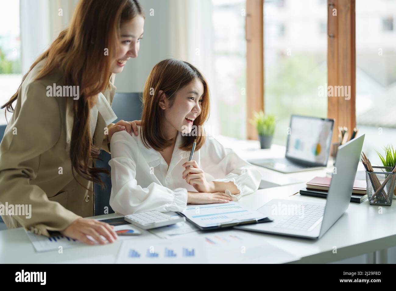 Deux femmes assis au bureau se sentent euphoriques gagner loterie en ligne, heureuse femme asiatique overjoyed obtenir le courrier à l'ordinateur portable étant promu au travail, fille biracial stupéfait Banque D'Images